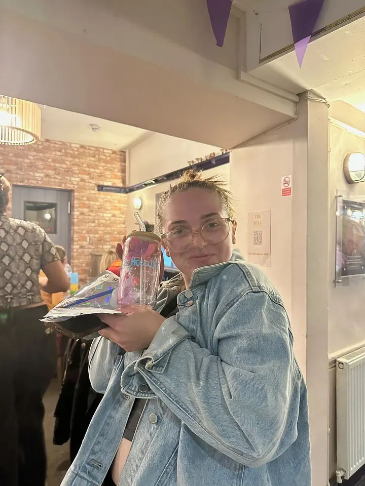A guest holding her finished painted tumbler up to her cheek