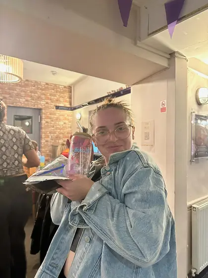 A guest holding her finished painted tumbler up to her cheek