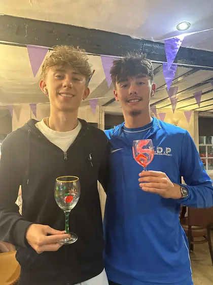 Two guests holding up the wine glasses they have painted